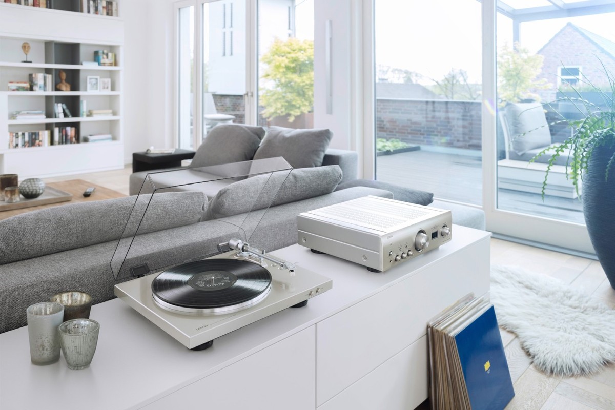 Giradischi Denon DP-300F argento e amplificatore abbinato su un mobile bianco del soggiorno