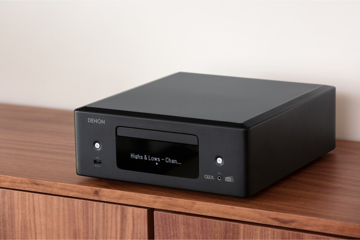 Black CD receiver on a walnut sideboard against a light wall