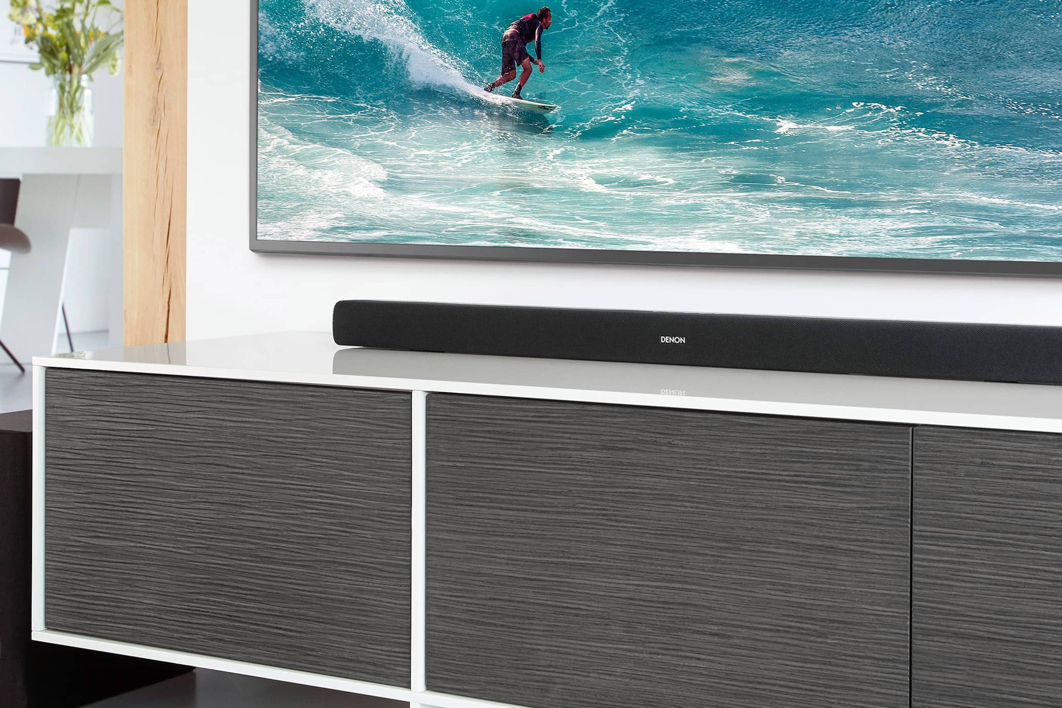 Soundbar su un mobile TV grigio, scena di surf sullo schermo