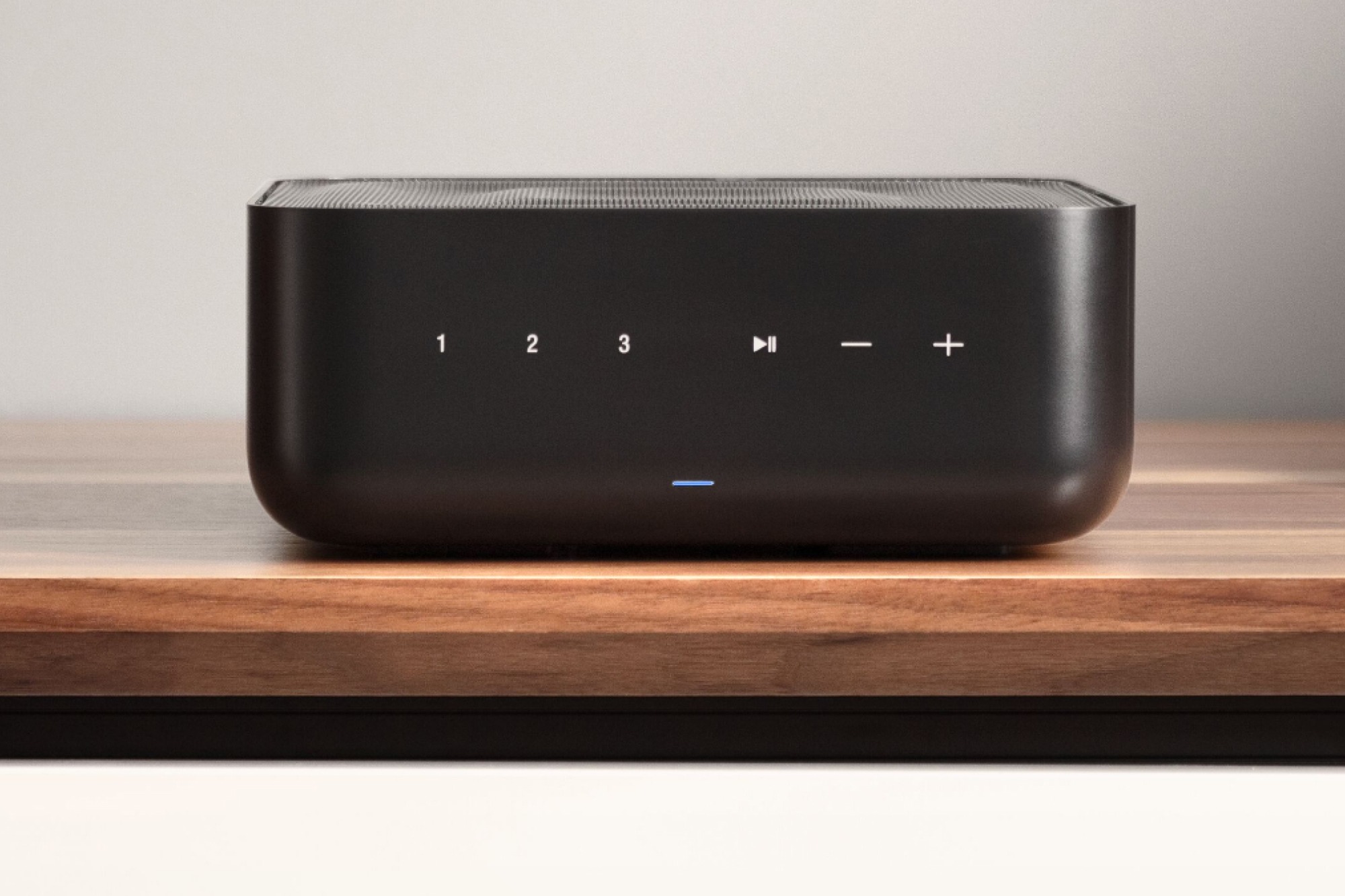 Frontale di un amplificatore di rete nero con i tasti di preselezione, su un mobile in legno