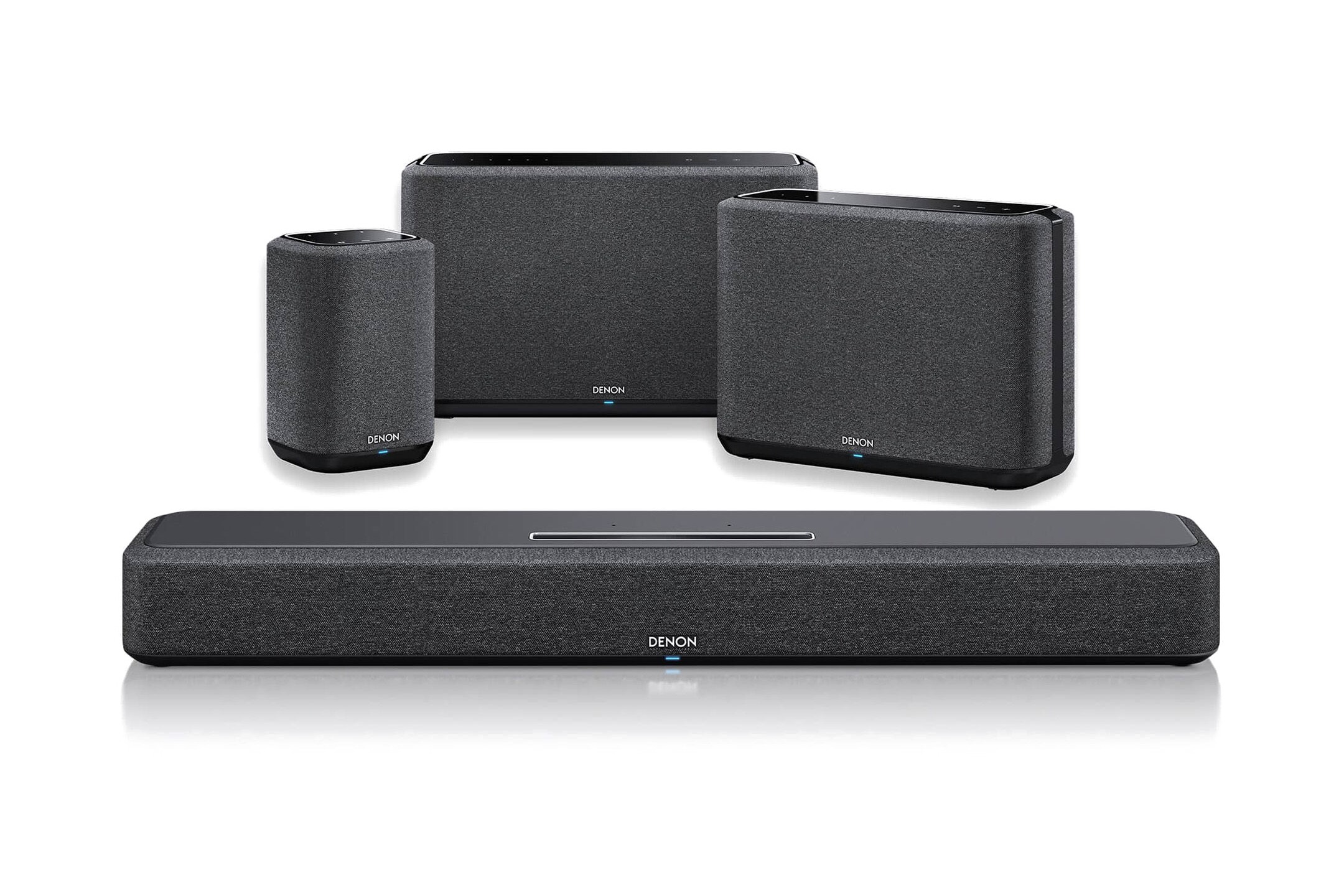 Soundbar und drei kabellose Lautsprecher derselben Serie vor weissem Hintergrund