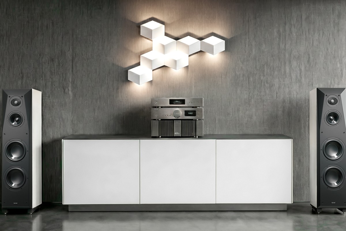 Pair of black and white floorstanding speakers flanking a cabinet in a contemporary room