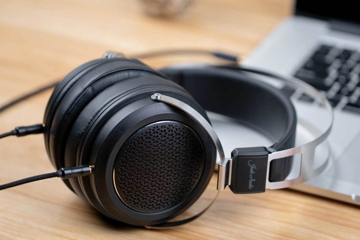FiiO JT1 headphones resting on a desk next to a laptop