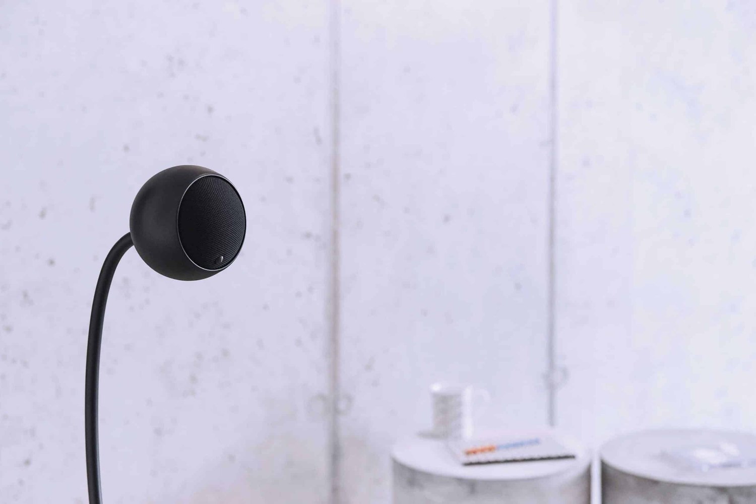 Diffusore nero su un supporto flessibile davanti a un muro di cemento