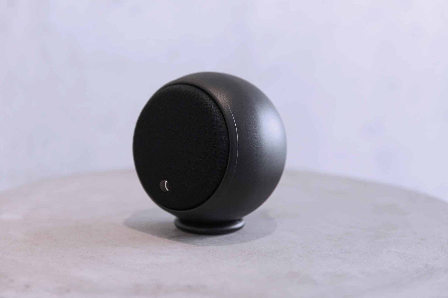 Enceinte noire posée sur un guéridon en béton clair