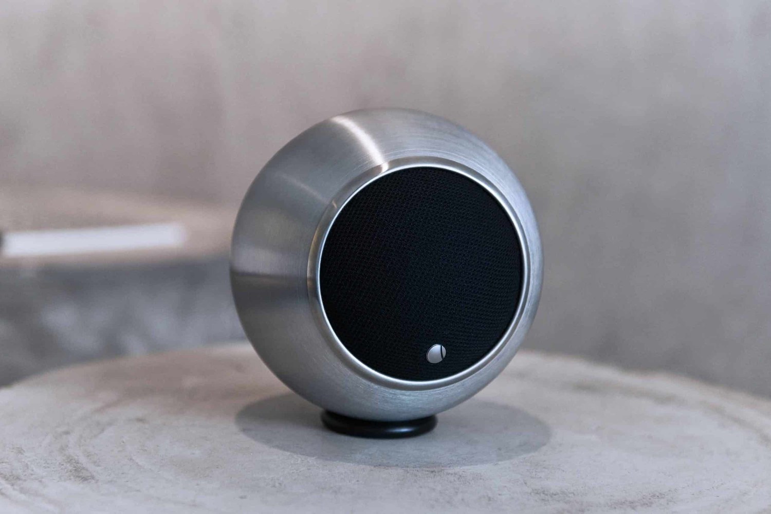 Enceinte sphérique argentée posée sur un plateau en bois