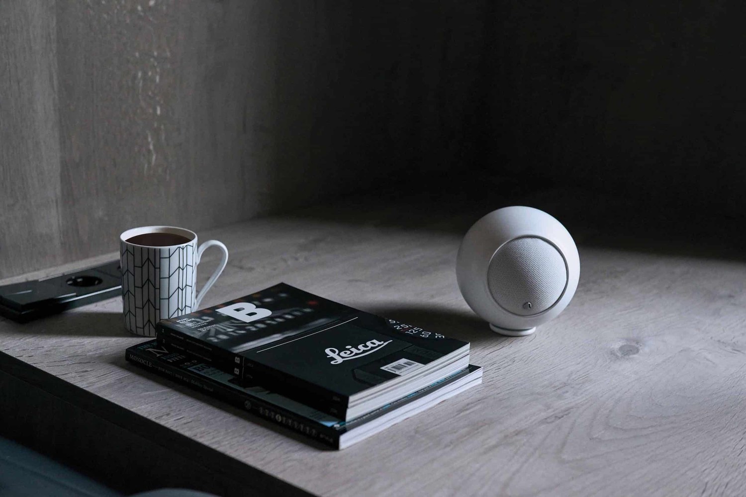 Enceinte blanche sur une étagère à côté d'une tasse et de livres