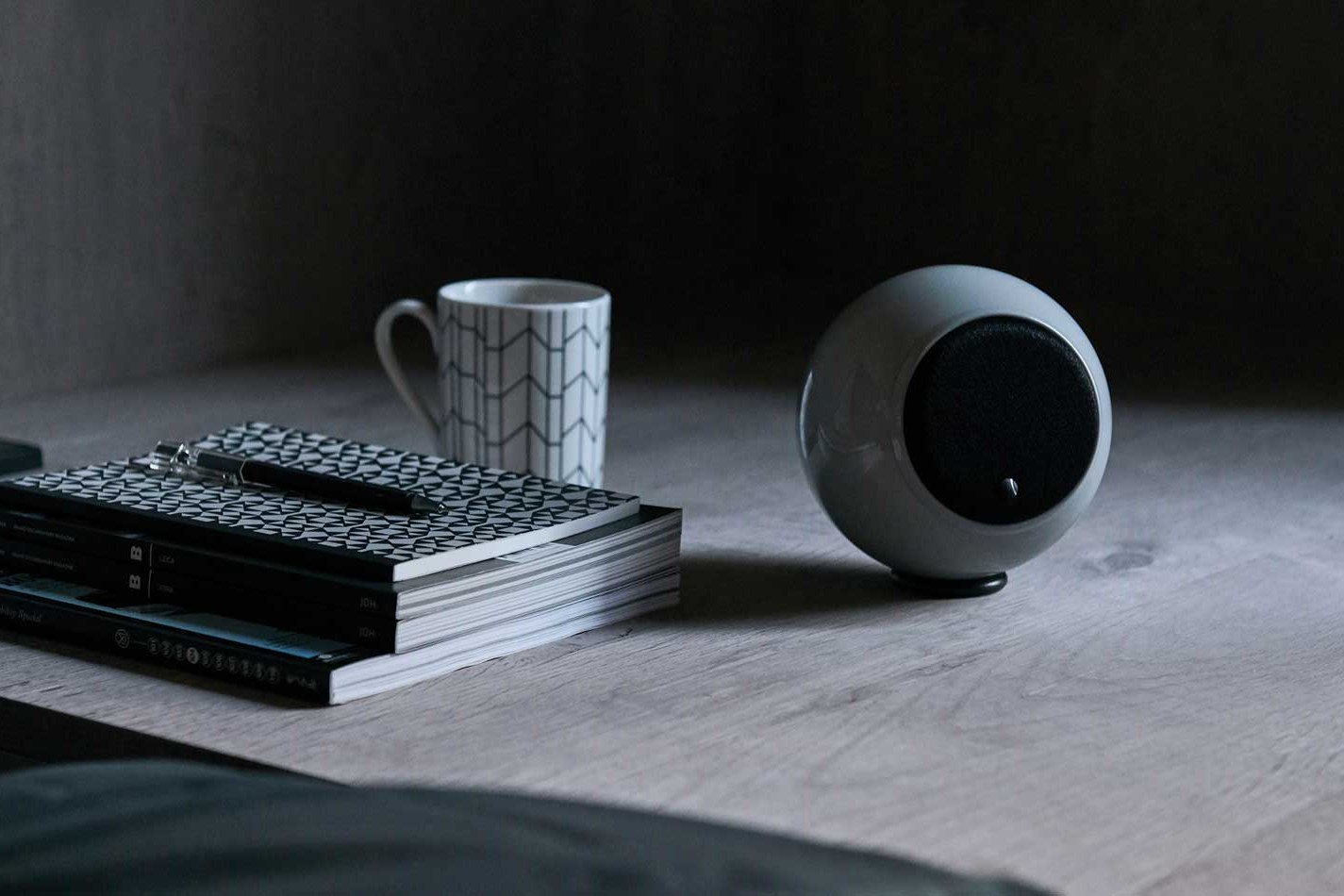 Enceinte sombre sur une étagère à côté d'une tasse et de livres