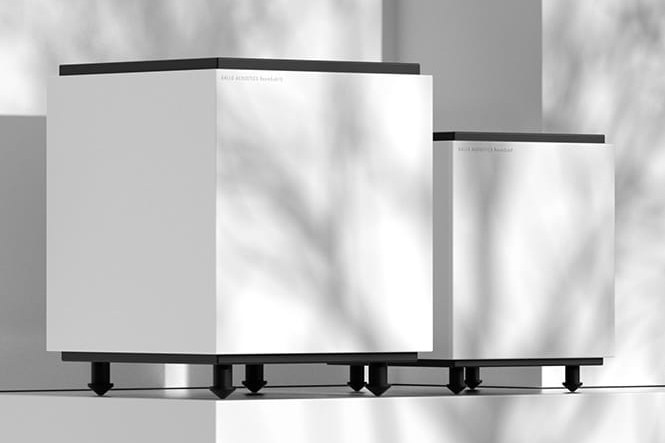 Zwei weisse Subwoofer auf einem Regal in gedämpftem Licht