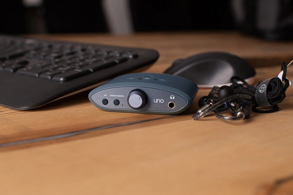 Kleiner DAC auf einem Holzschreibtisch zwischen Tastatur, Maus und Ohrhörern