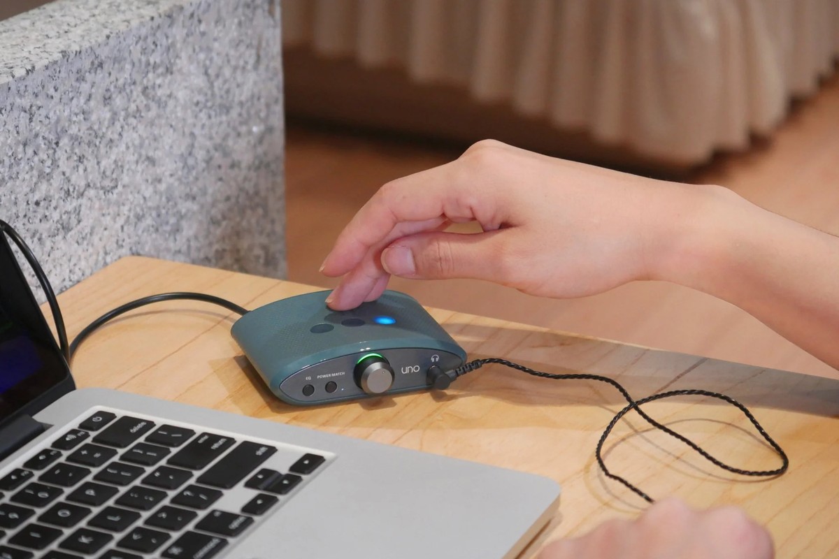 Hand drückt eine Taste auf der Oberseite, Kabel zum Laptop