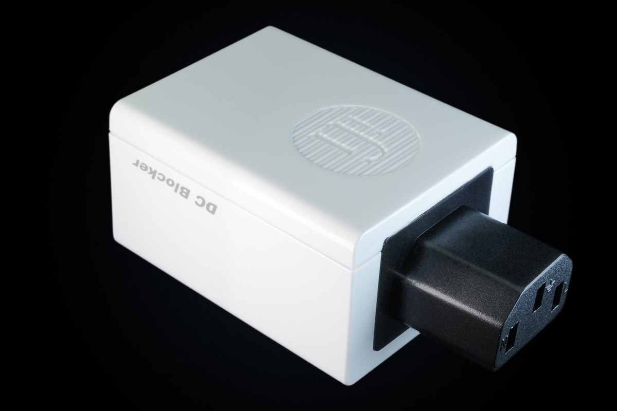 White adapter with a black female IEC socket, three-quarter view on a black background