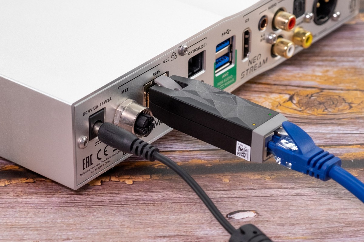 Netzwerkfilter an der Rückseite eines grauen Streamers, blaues Ethernet-Kabel
