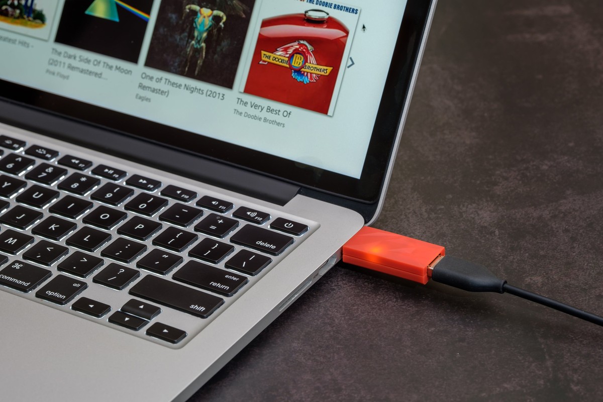 Small orange adapter plugged into the side of a laptop, black cable