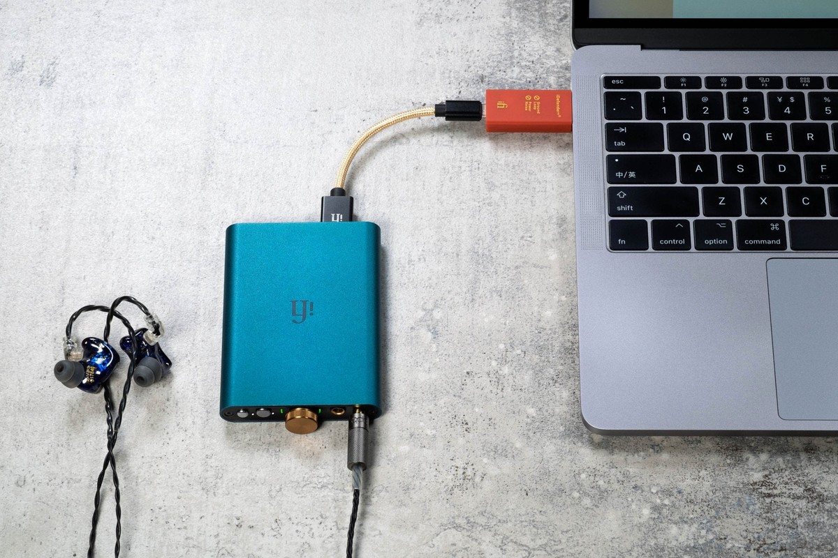 Orange adapter between a laptop and a blue portable DAC with earphones