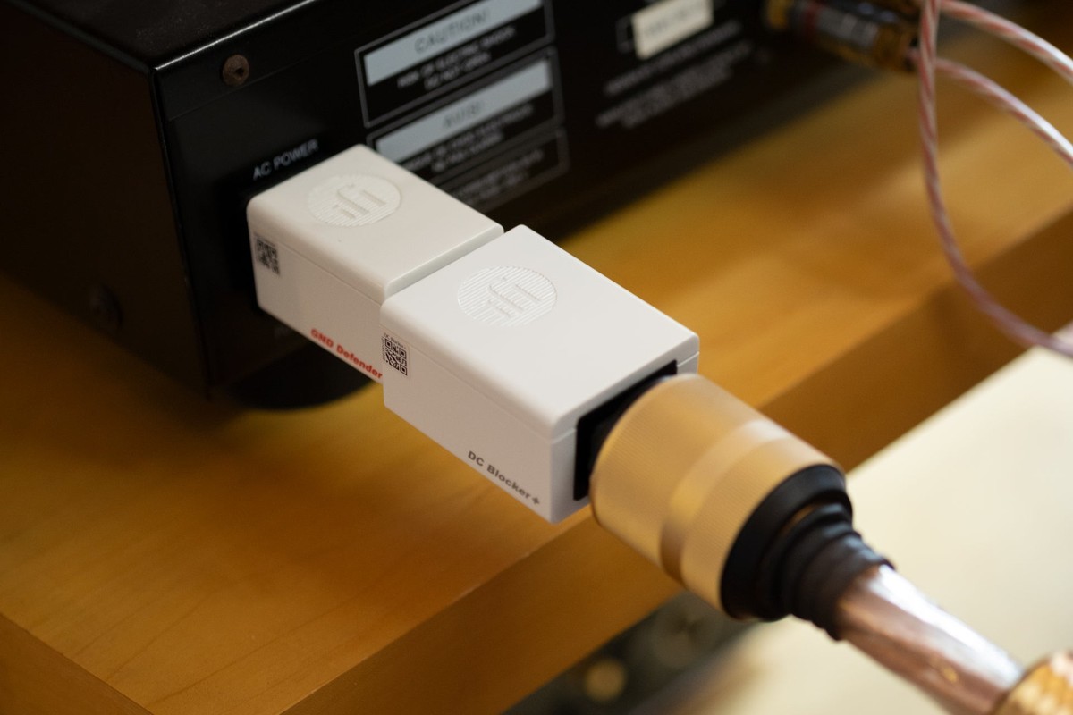 Zwei weisse Gehäuse in Reihe am Netzeingang eines Geräts, kupferfarbenes Netzkabel