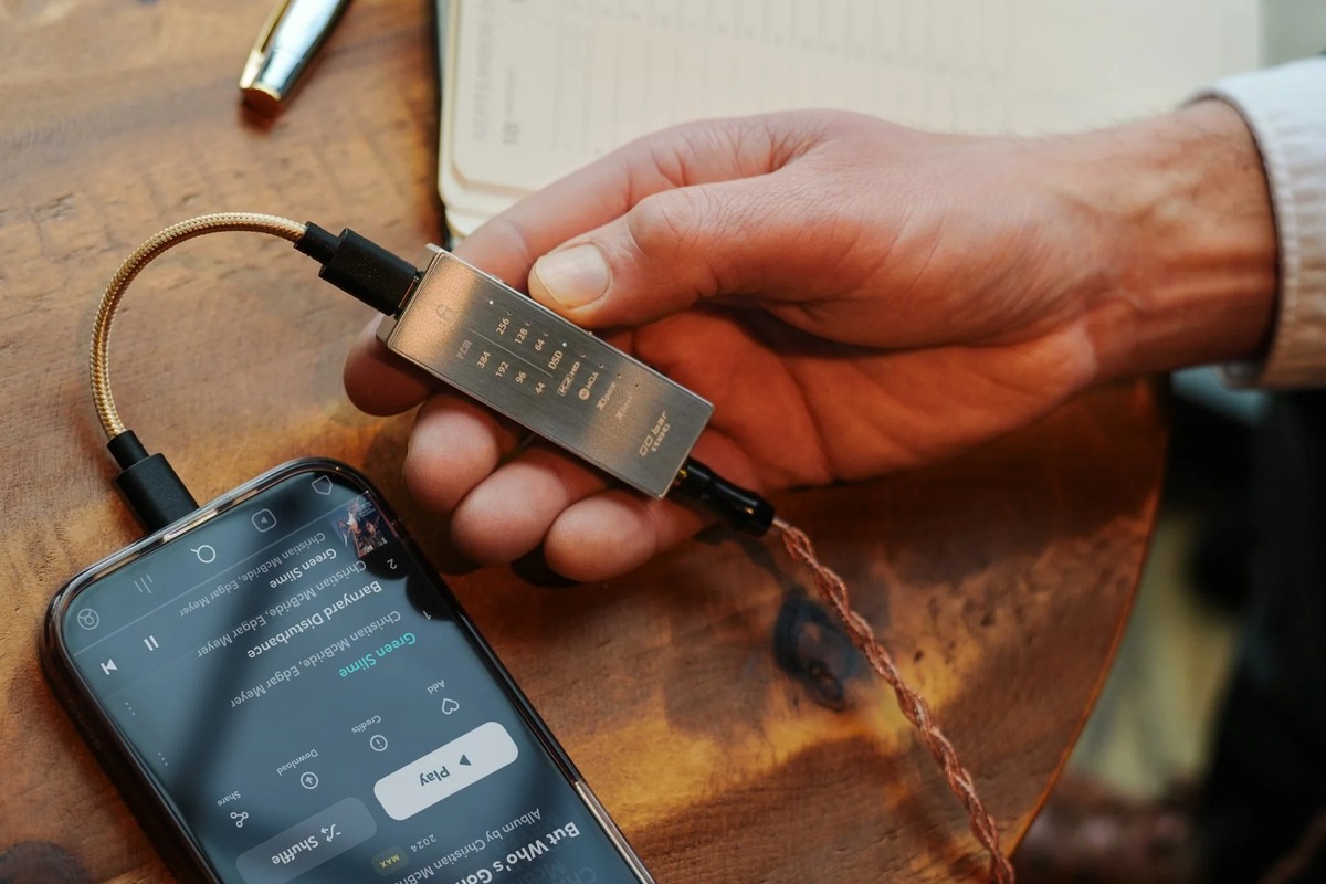 Hand holding the steel unit linked by a braided cable to a smartphone