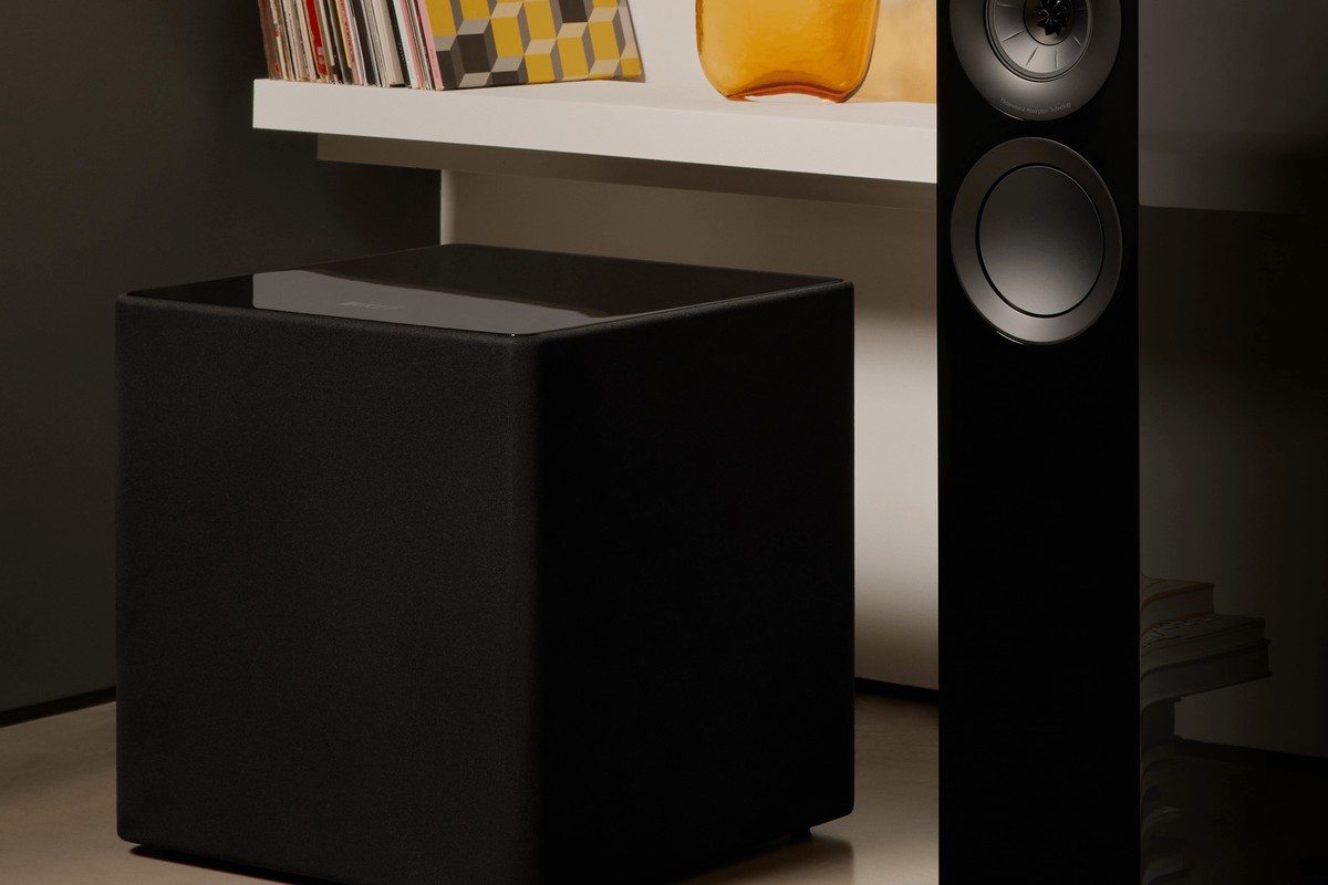 KEF Kube 15 MIE noir au sol dans un salon, à côté d'une enceinte colonne