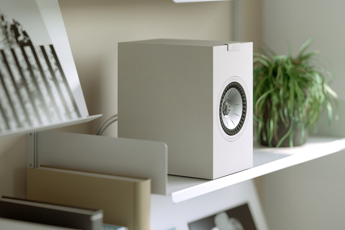 Enceinte blanche posée sur une étagère près de plantes vertes