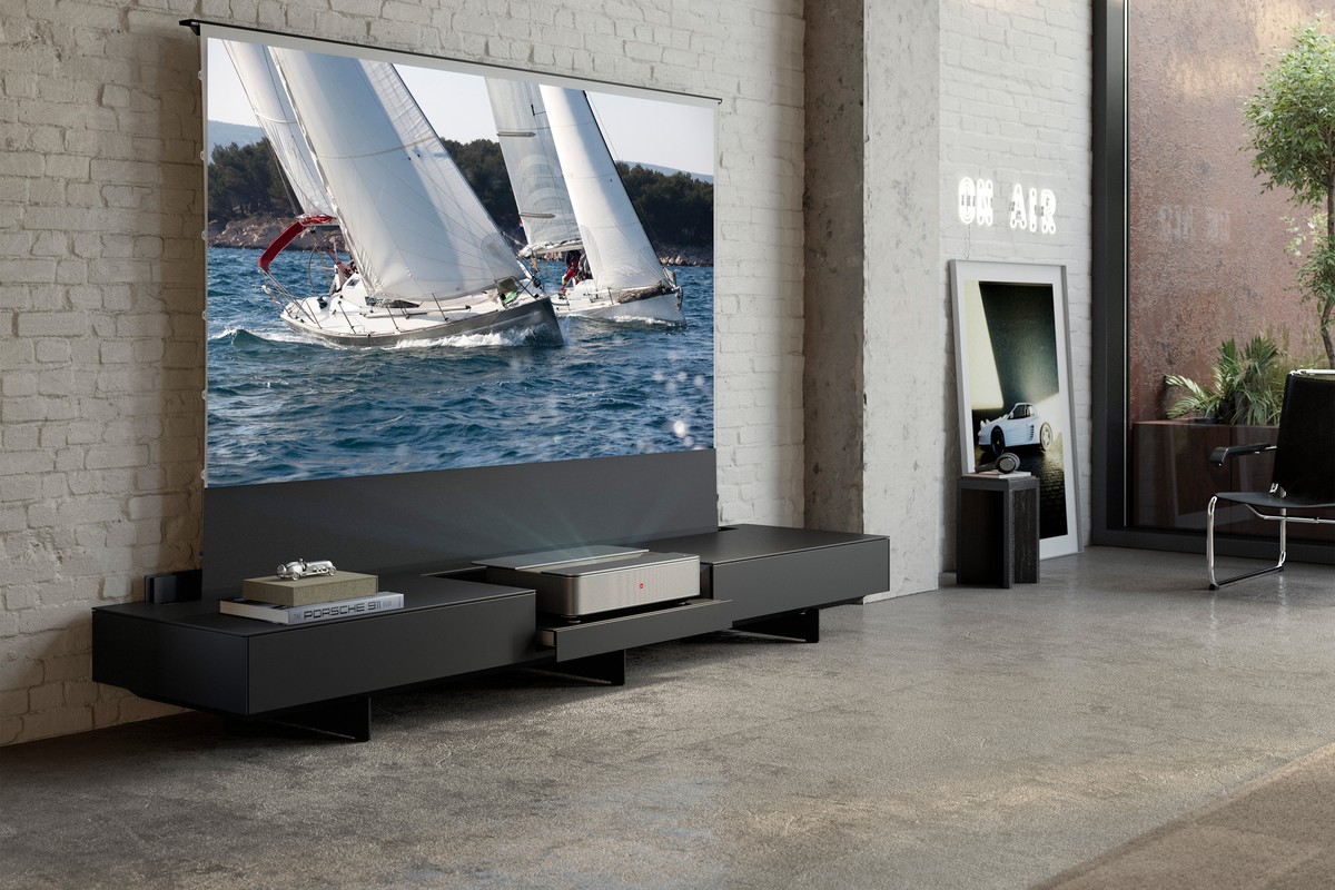 Projector in a low black cabinet, screen with sailing boats just above
