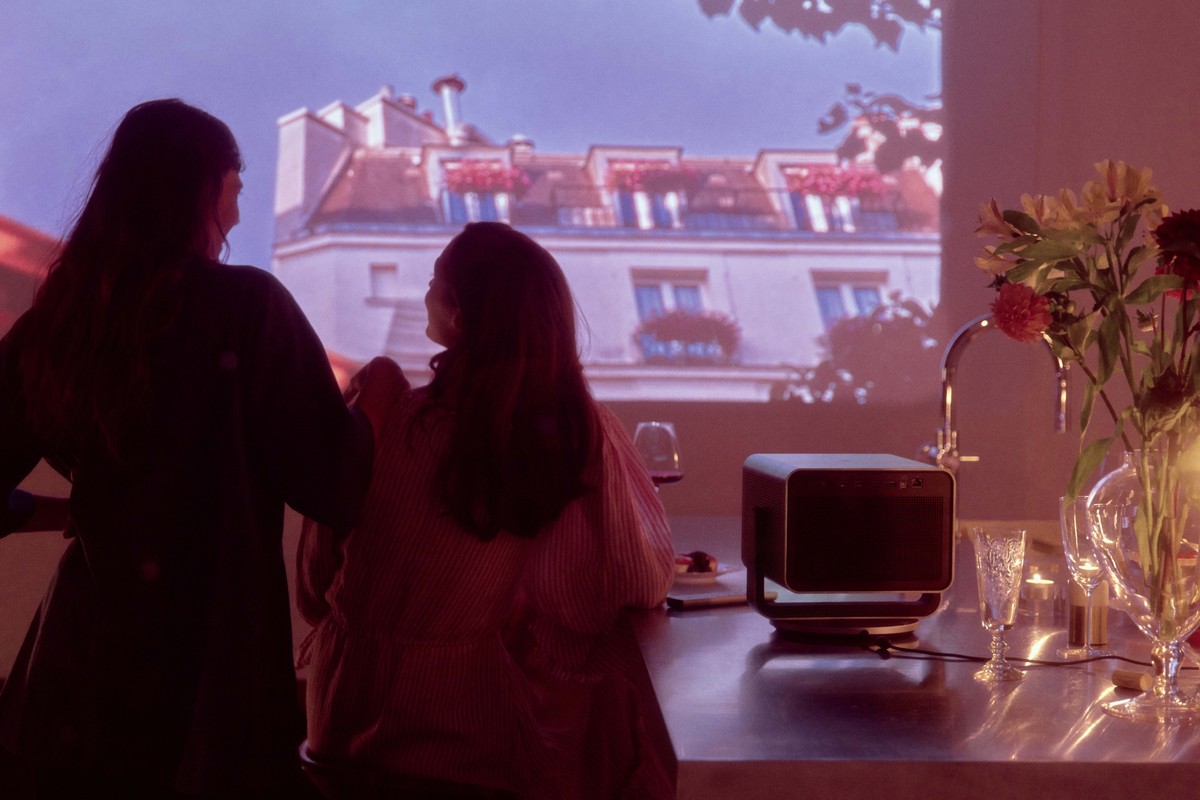 Compact projector on a worktop, colourful image projected on the wall
