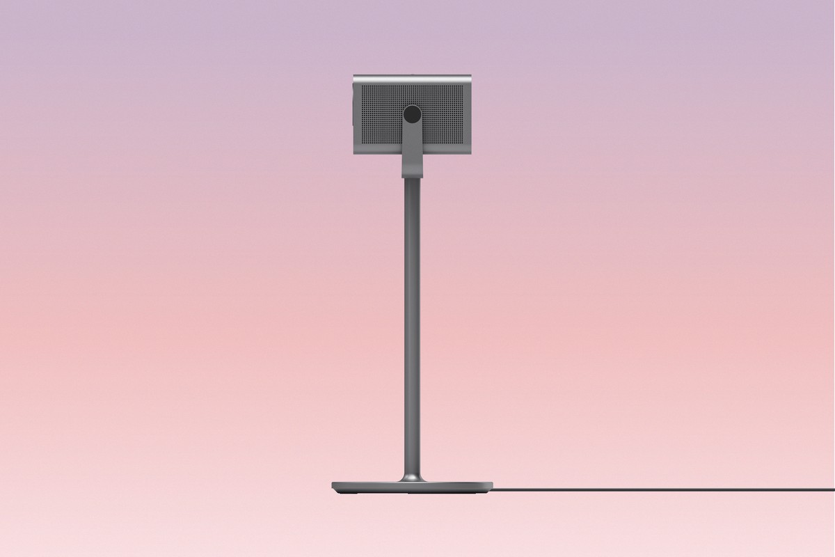 Compact projector mounted on a floor stand, pink gradient background