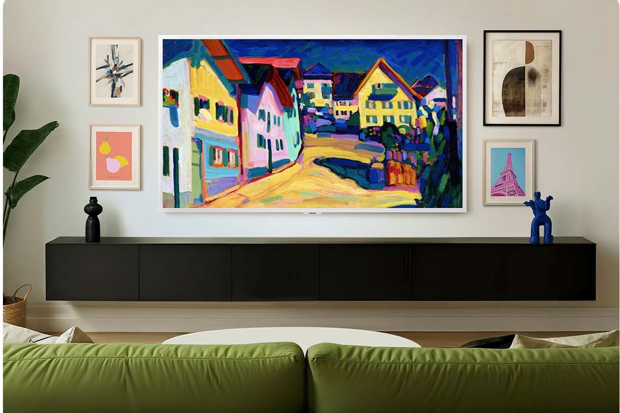 Fernseher mit weissem Rahmen an der Wand über einem niedrigen schwarzen Sideboard und einem grünen Sofa
