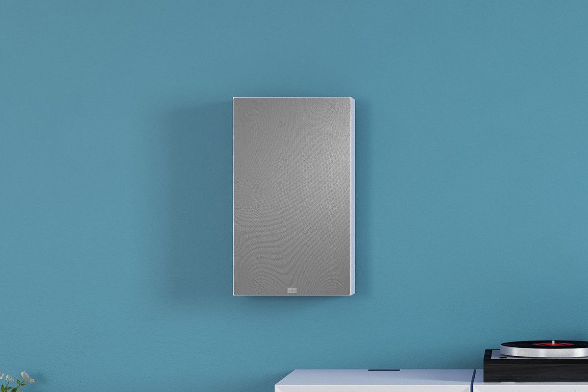 Wall speaker with grey grille mounted on a wall