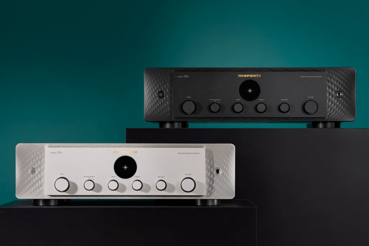 Due amplificatori hi-fi, uno nero e uno argento oro, affiancati su basi nere davanti a uno sfondo blu-verde