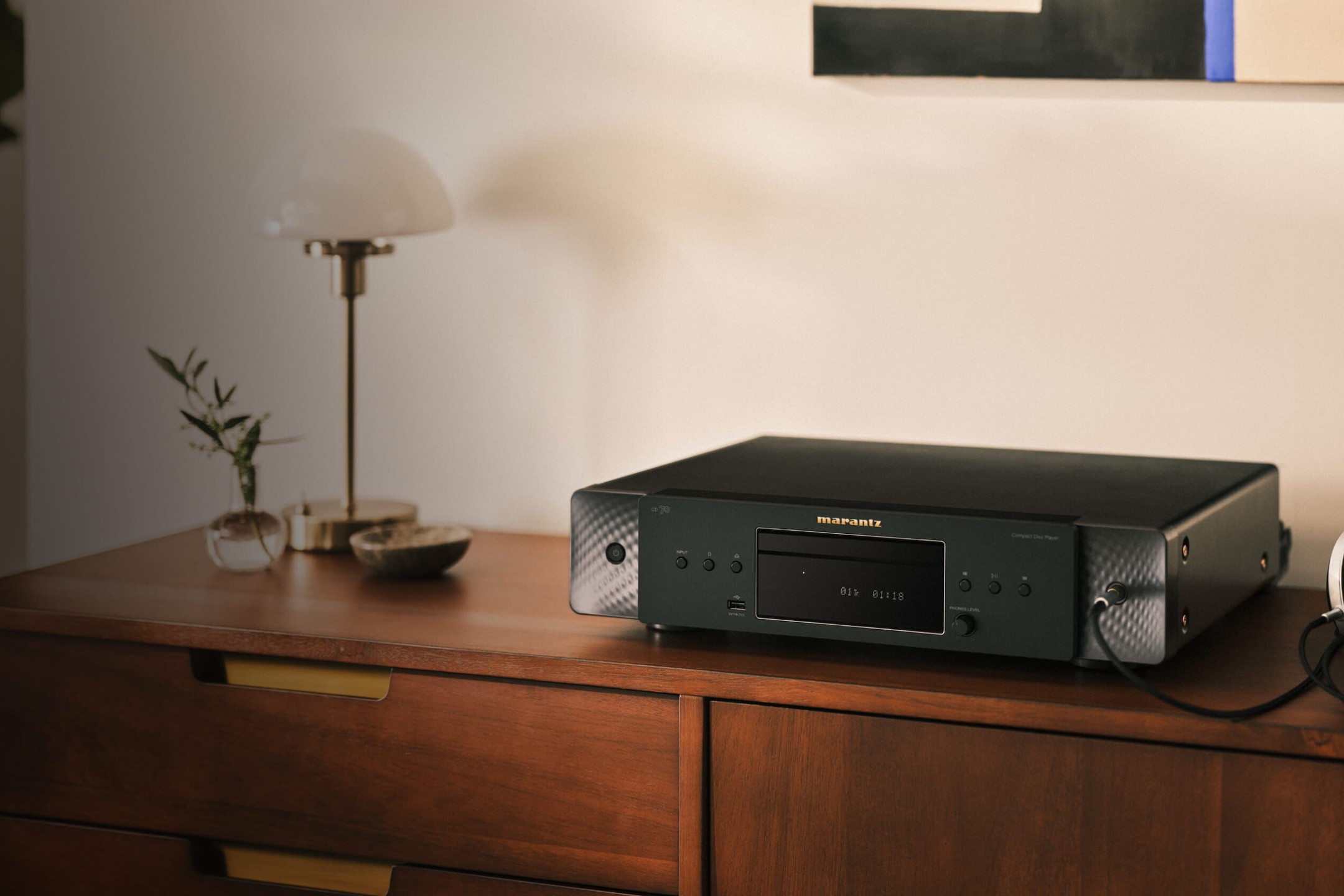 Schwarzer CD-Player auf einer Holzkommode neben einer Lampe