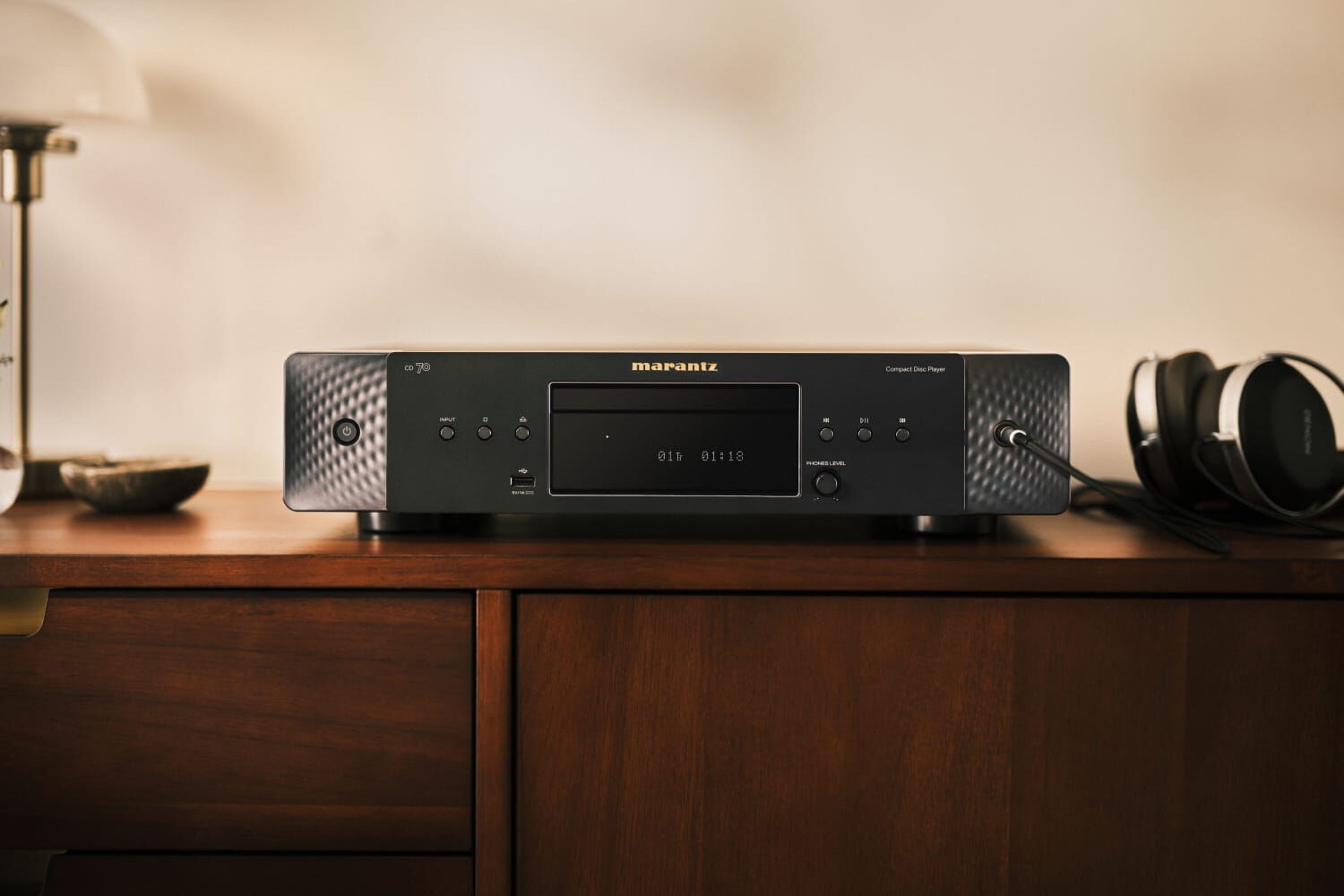 Schwarzer CD-Player auf einem Holzmöbel, Kopfhörer an der Front angeschlossen