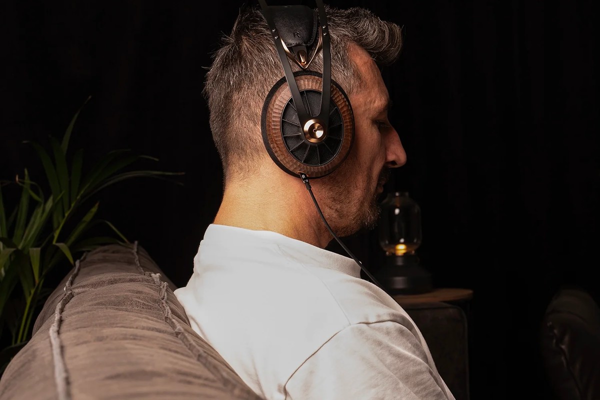 Uomo seduto su un divano che ascolta musica in cuffia