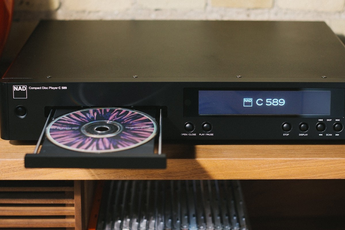 Compact disc nel cassetto aperto del lettore, con il display acceso, su un mobile in legno
