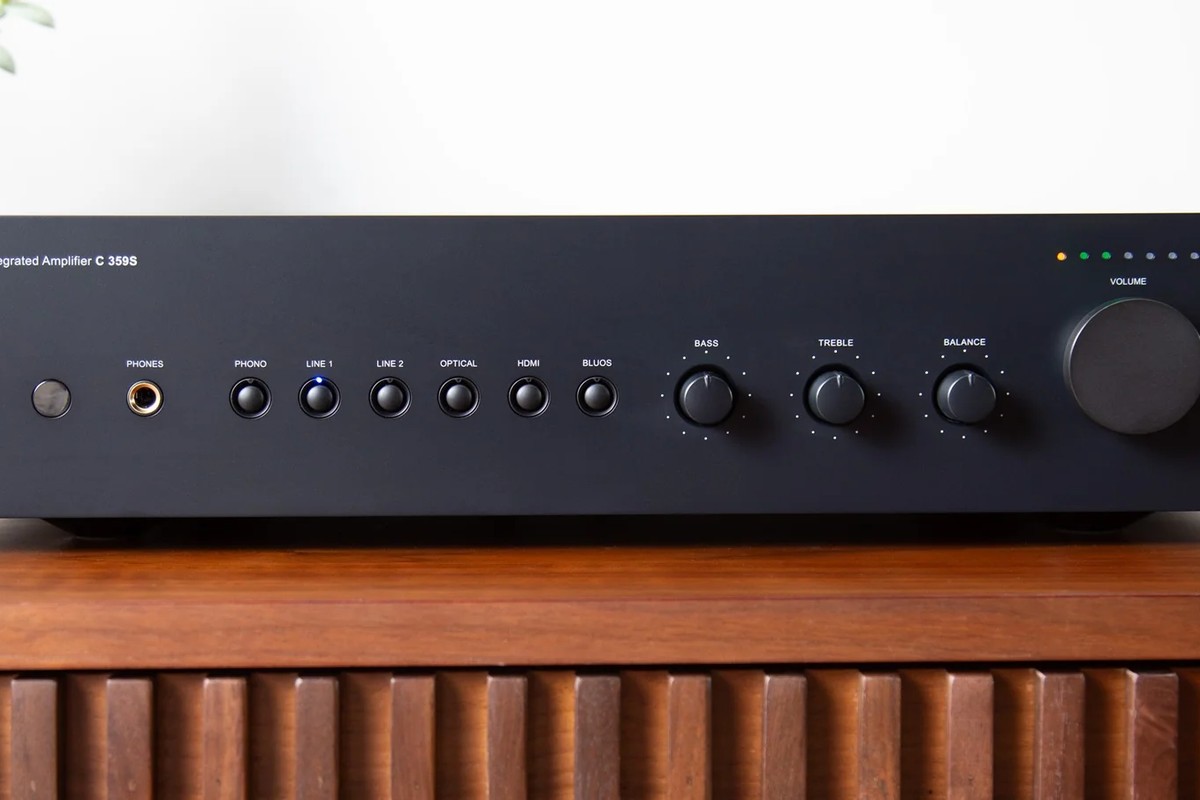 Façade du NAD C 359S avec ses touches de sources et sa prise casque, sur un buffet en noyer