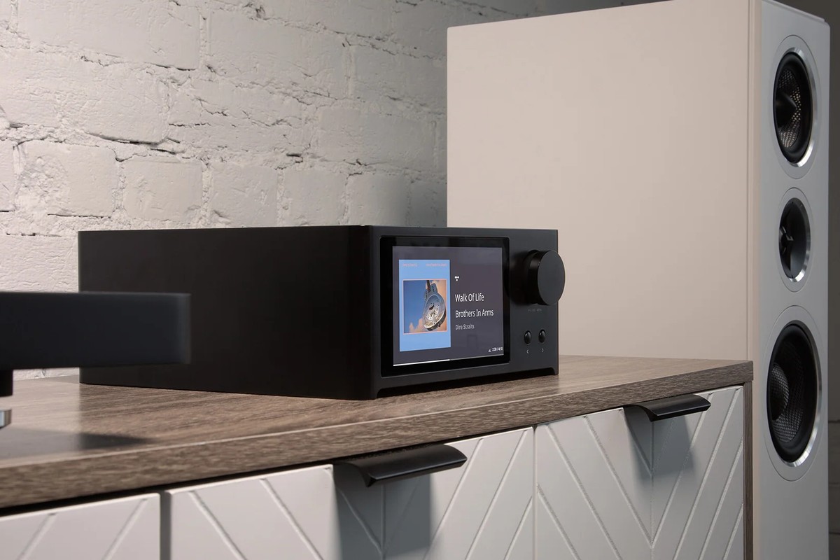 Amplifier on a white sideboard next to a floorstanding speaker