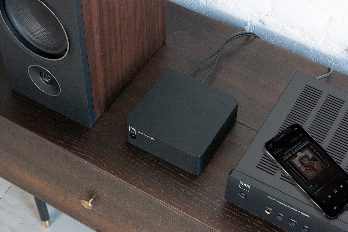 Streamer seen from above next to a speaker, with a smartphone resting on the amplifier beside it