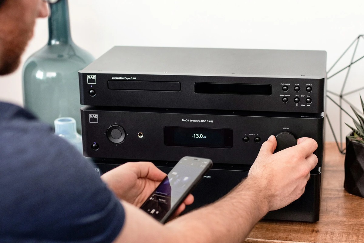 Mano che regola il volume del preamplificatore mentre la musica arriva dallo smartphone