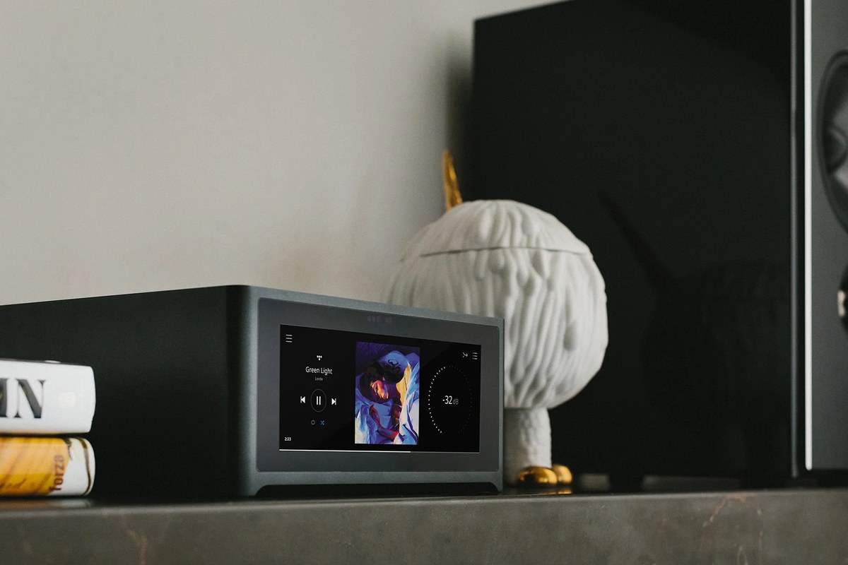 Touchscreen mit Albumcover auf einem Regal neben einem Lautsprecher