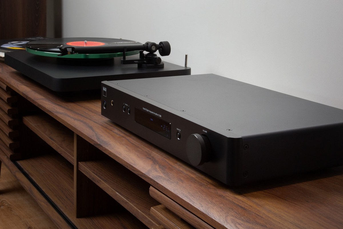 Amplificatore NAD C 328 su un mobile in legno accanto a un giradischi