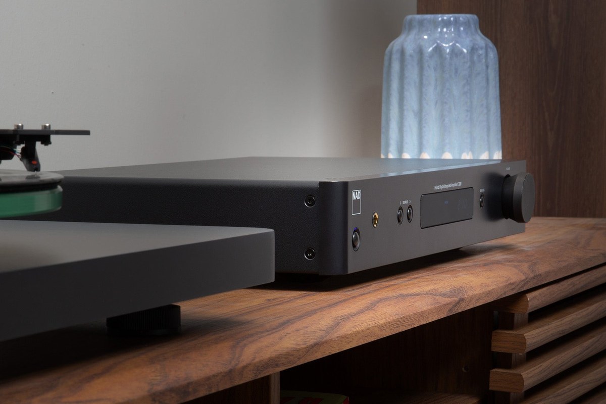 Amplificatore nero su un mobile in legno dietro un giradischi, vaso sullo sfondo