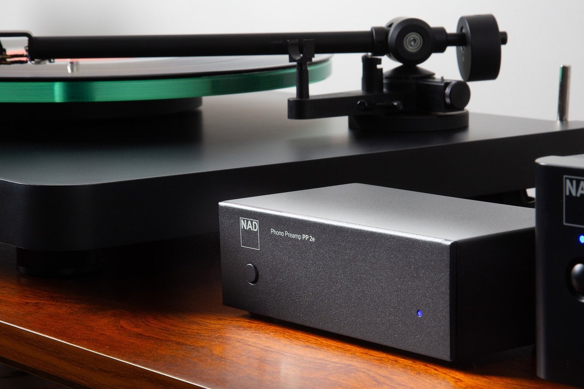 Préamplificateur phono NAD PP 2e à côté d'une platine vinyle sur un meuble en bois