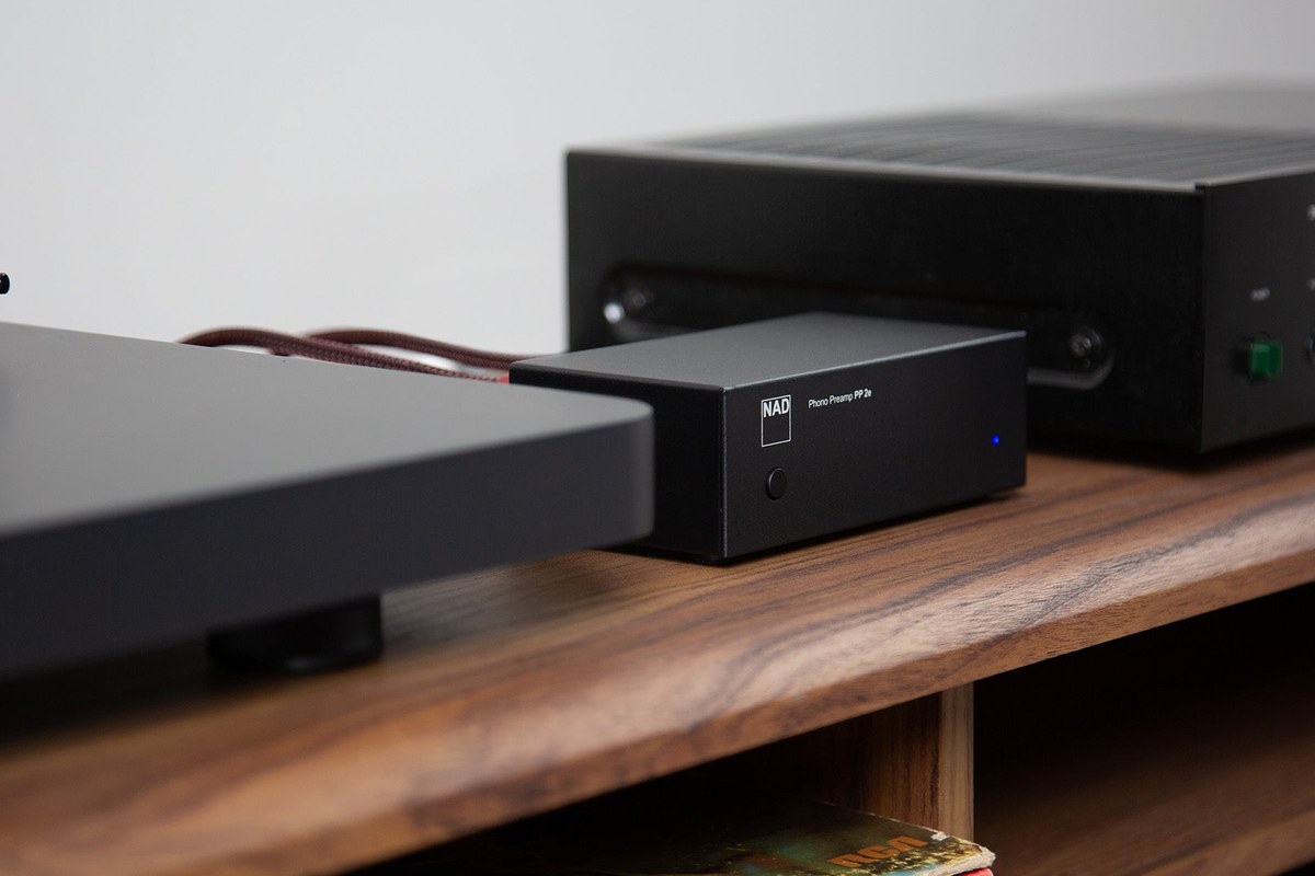 Petit boîtier noir entre une platine et un amplificateur, câbles phono branchés