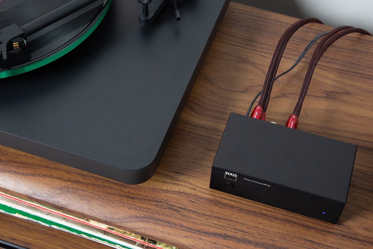 Préampli phono vu du dessus avec ses câbles RCA, posé près de la platine