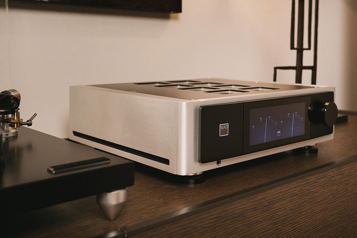 Amplificatore integrato argento accanto a un giradischi, display acceso
