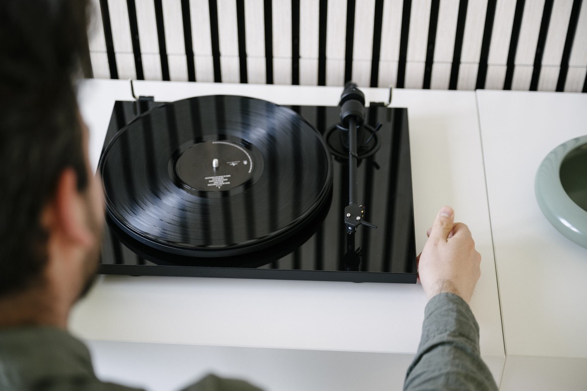 Hand placing a record on a black turntable