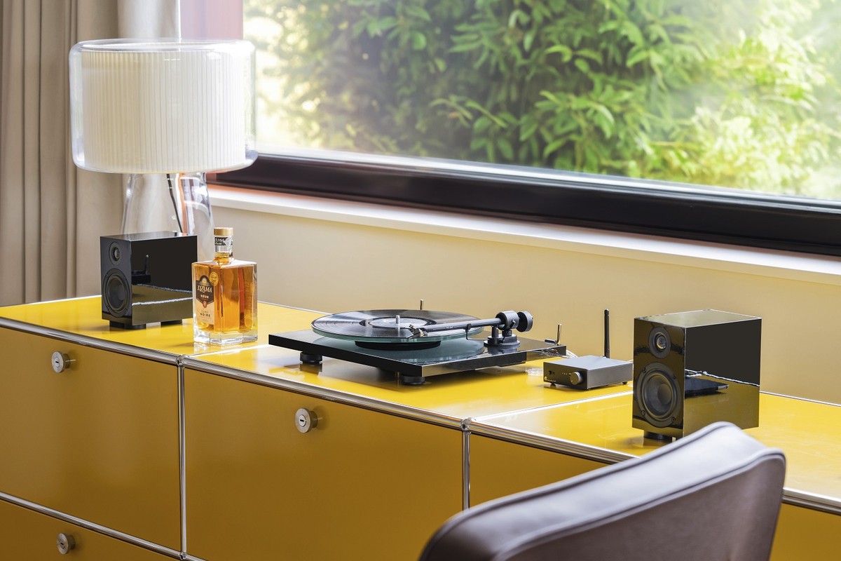 Turntable on a yellow sideboard near a window