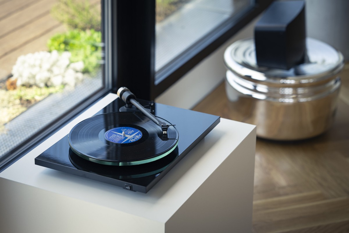 Platine noire et enceinte sur un meuble près d'une fenêtre