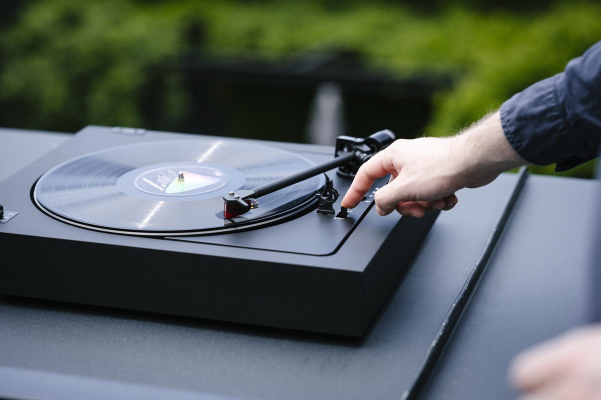 Main lançant la lecture sur une platine noire en extérieur
