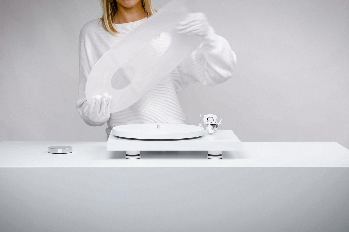 Person lifting the dust cover of a white turntable