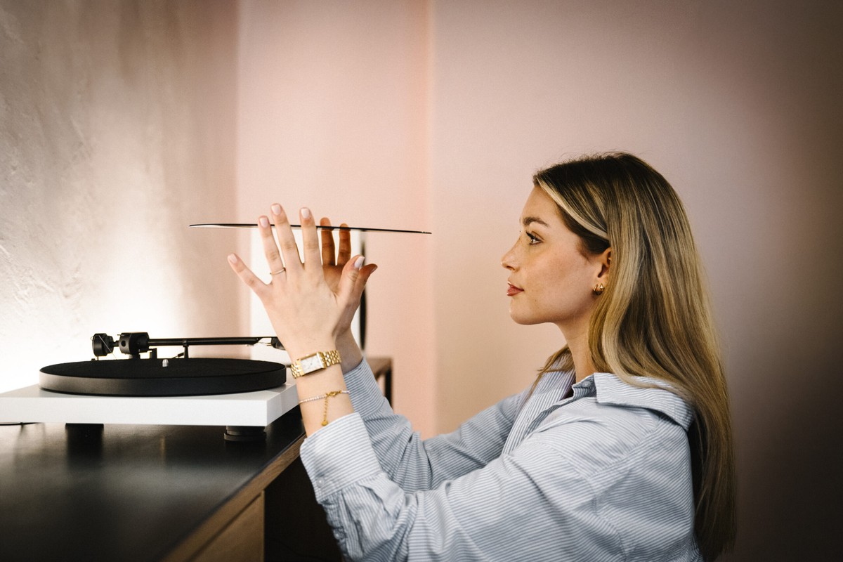 Woman holding a record in front of a white turntable